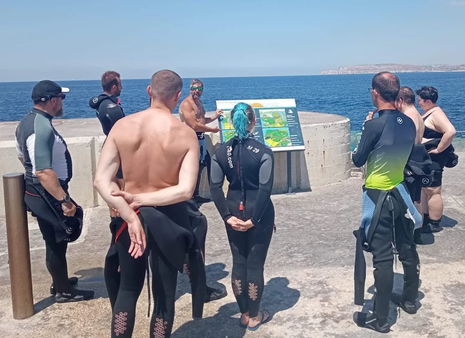 A dive briefing taking place on the shore before divers enter the water